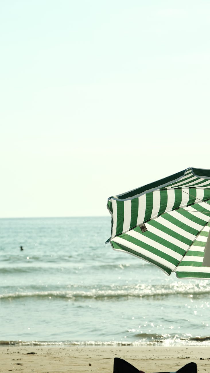 green striped beach umbrella by the sea